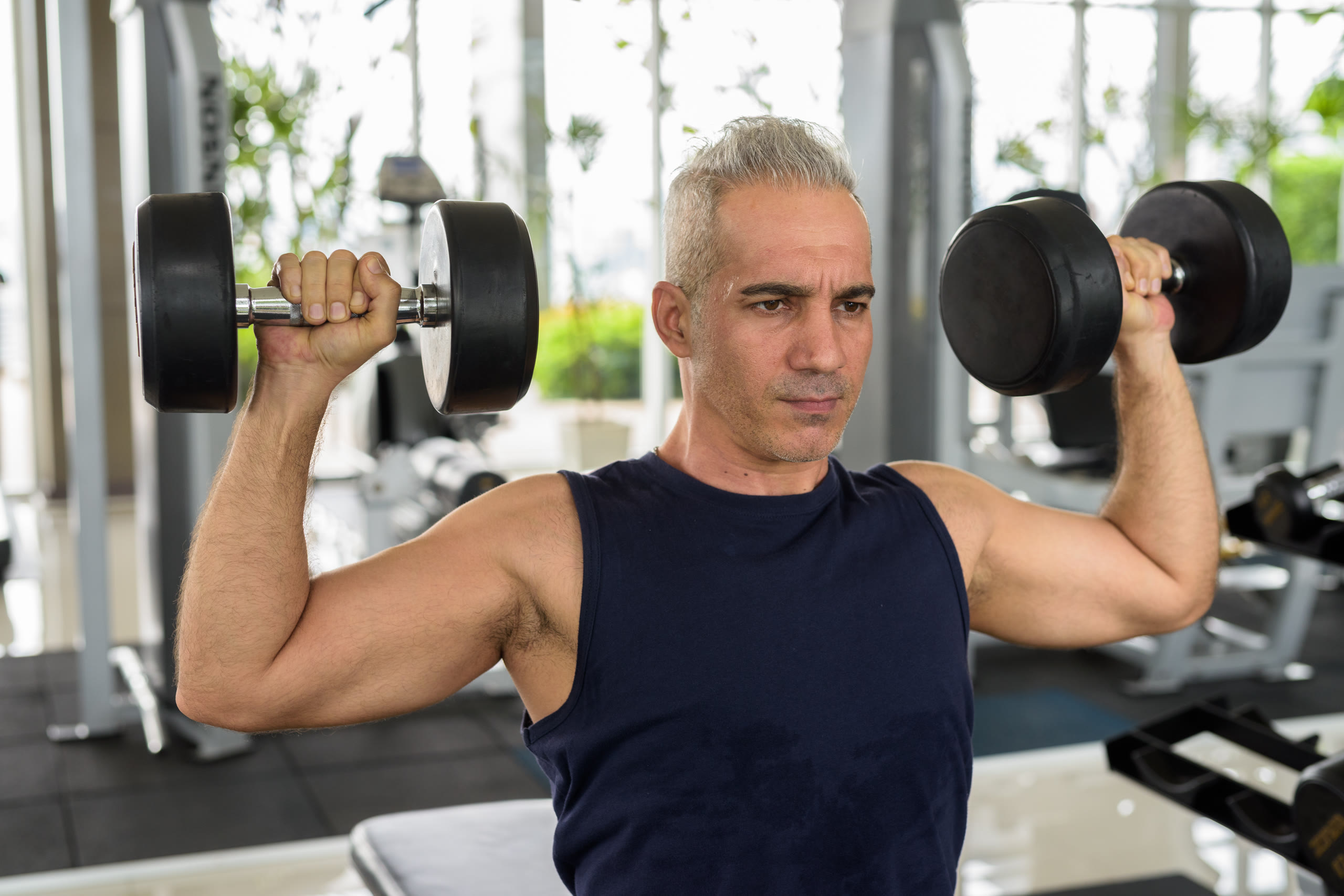 Hombre de mediana edad entrenando con mancuernas en el gimnasio
